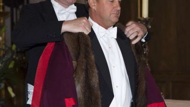 The outgoing Master, Charles Vernon, investing the new Master, Jonathan Hindle, with his gown and badge